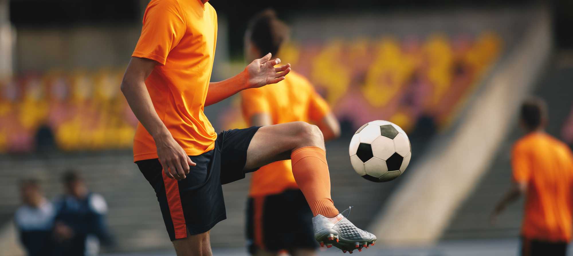 Person kicking football into the air