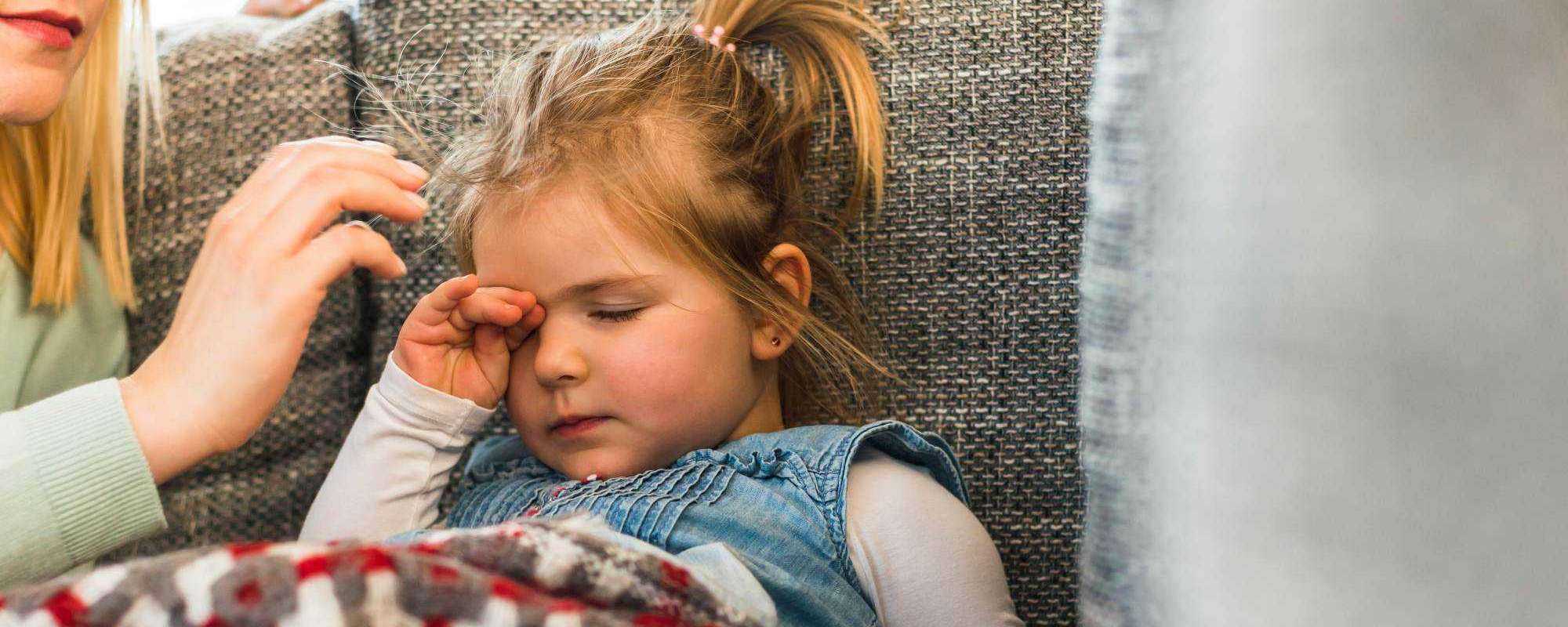 child with blanket rubbing her eyes