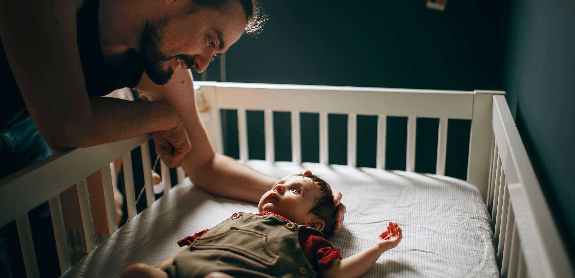 Father Interacting with Baby in Crib