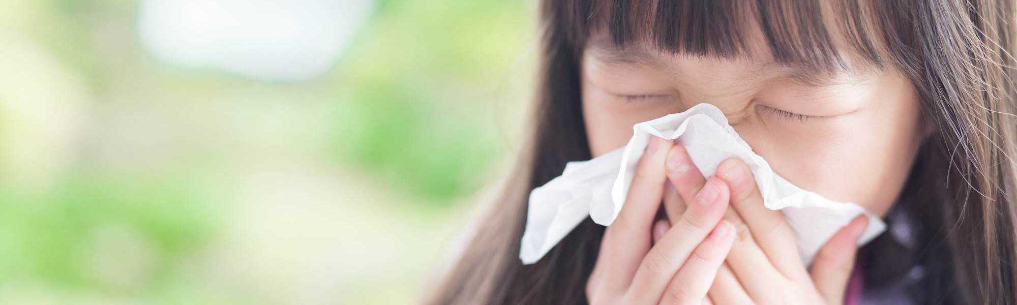 child sneezing into a tissue