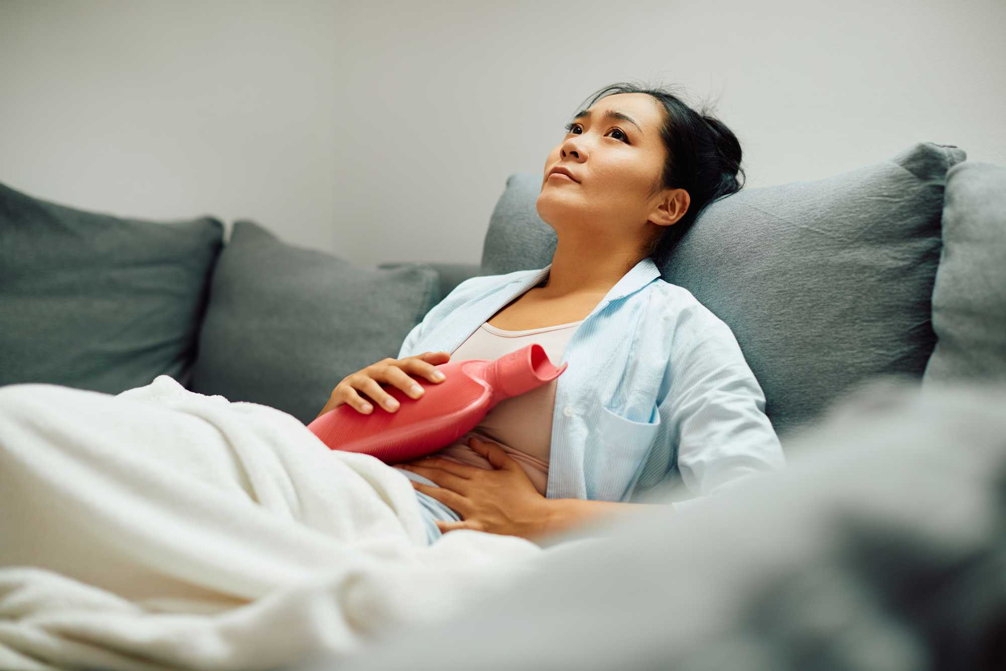 Woman holding hot water bottle to her stomach