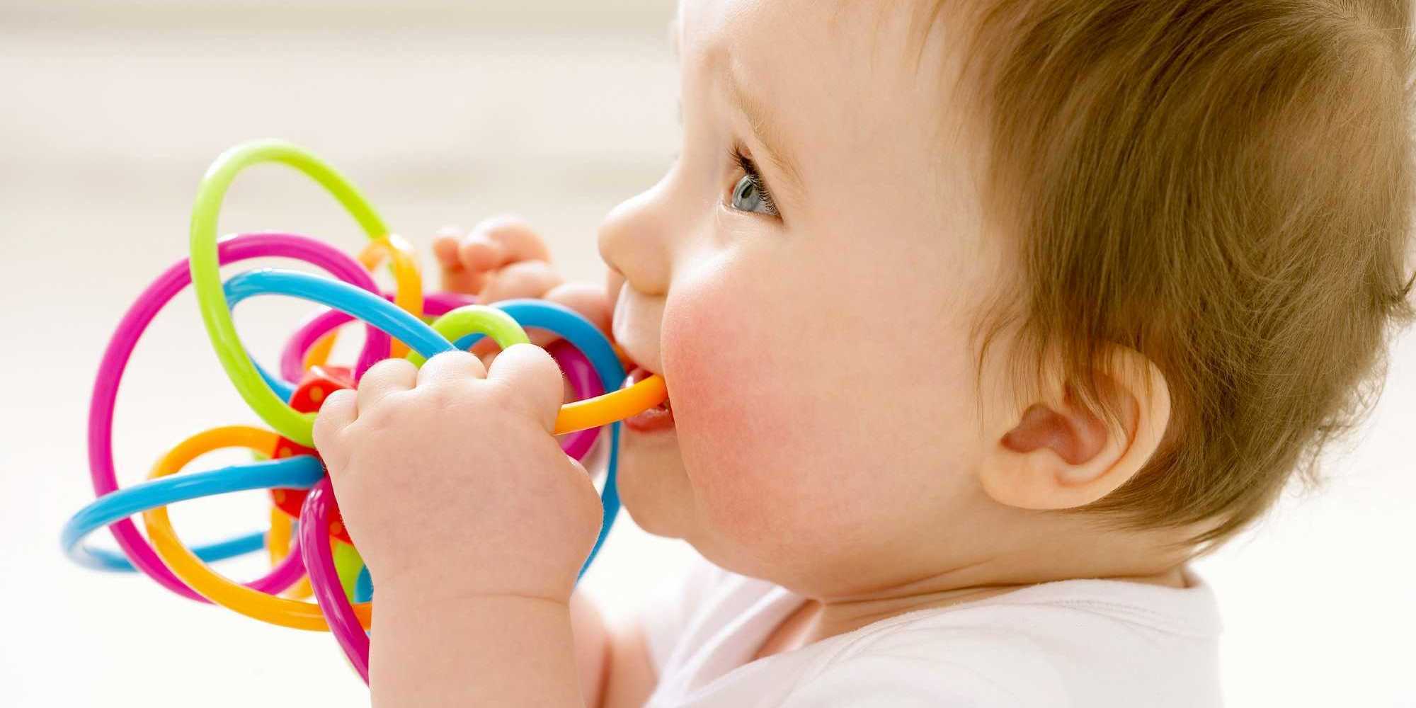 toddler chewing on colourful toy